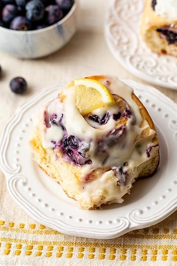 blueberry lemon roll with cream cheese icing on a white plate.