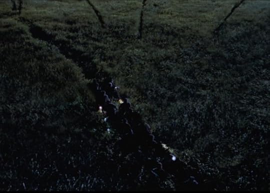 Frame from the Lost World Jurassic Park movie. It shows a party of folks, at night, walking through tall grass, while the outlines of Raptors converge on them.