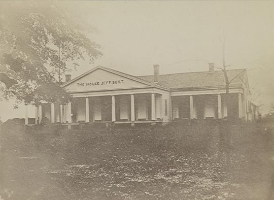 Sepia-toned photo on a long one-story house with many columns. It is slightly uphill and in middle distance from photographer.