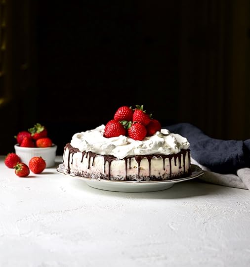 Classic Neapolitan ice cream cake with a chocolate cookie crust, layers of pink strawberry and vanilla ice cream, topped with a luscious chocolate ganache drip, clouds of whipped cream, and fresh whole strawberries.