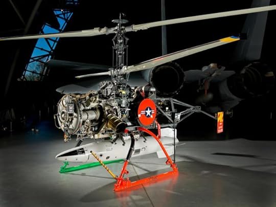 A small metal helicopter carries a large white torpedo that looks almost too heavy for it to carry.