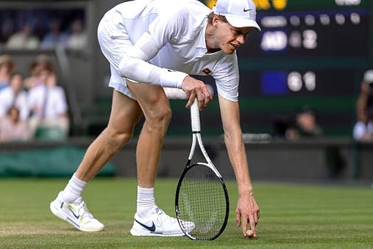 Jannik Sinner of Italy picks up a popped champagne cork which landed on the court during his match against Carlos Alcaraz of Spain in the Gentlemen's...