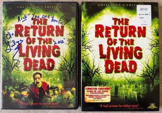DVD of The Return of the Living Dead. Next to it is the slipcase. The slipcase glows in the dark. Both DVD and slip case show a dark, green-lit cemetery, but the DVD has zombies coming out from the ground. The DVD is signed in blue ink 