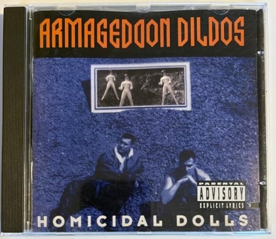 Cover is a photo tinted blue. It shows the two band members sitting on the ground. Above them is a picture showing three blow up dolls.