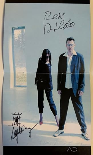 Booklet shows Uwe K. and Malin standing in an empty white room save for a glass door behind them. In black ink it is signed 