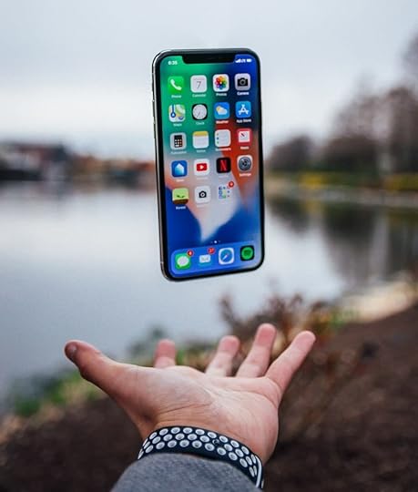 silver iPhone X floating over open palm