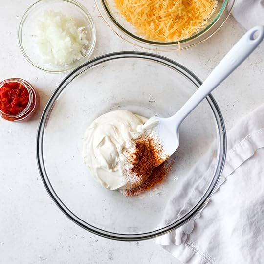 Mixing mayonnaise, cream cheese, and spices for pimento cheese dip.