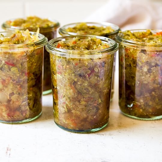 Five glass jars filled with homemade spiced zucchini relish, showcasing the chunky texture and vibrant colors of the relish.