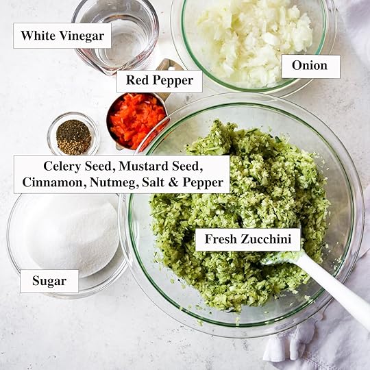 Overhead shot of several small glass jars filled with homemade spiced zucchini relish, showcasing the finely chopped vegetables and a glistening texture, ready for storage.