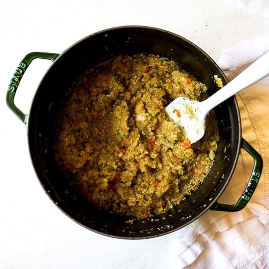 Thickened, cooked homemade spiced zucchini relish in a green enamel Dutch oven with a white spatula, showing the final texture of the simmered condiment.