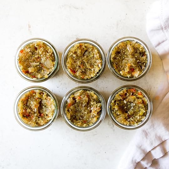 Top-down view of six small glass jars filled with fresh homemade spiced zucchini relish, showcasing the chunky texture and ready for storage or serving.