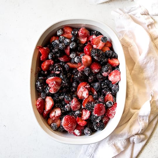 Mixed berries, includingstrawberries, blueberries, andblackberries, lightly coated withsugar and cornstarch, poured intoa white baking dish, ready for crumble assembly.