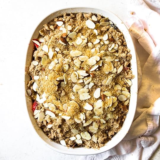 Unbaked Mixed Berry Crumblein a white oval baking dish,generously topped with a goldenstreusel, sliced almonds, andsparkling Demerara sugar,ready for the oven.
