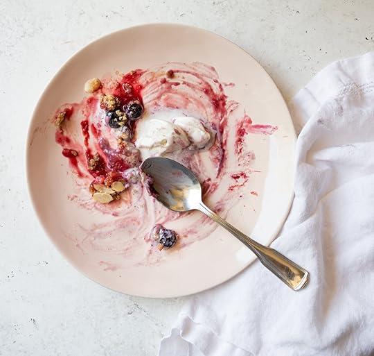 An empty pink plate with remnantsof a delicious Mixed Berry Crumble,melted vanilla ice cream, and a spoon, showing it was thoroughly enjoyed.