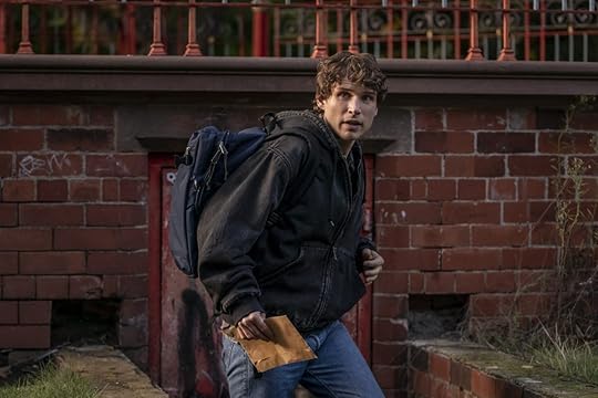 A young man with a backpack walking by a brick building on Talamasca: The Secret Order