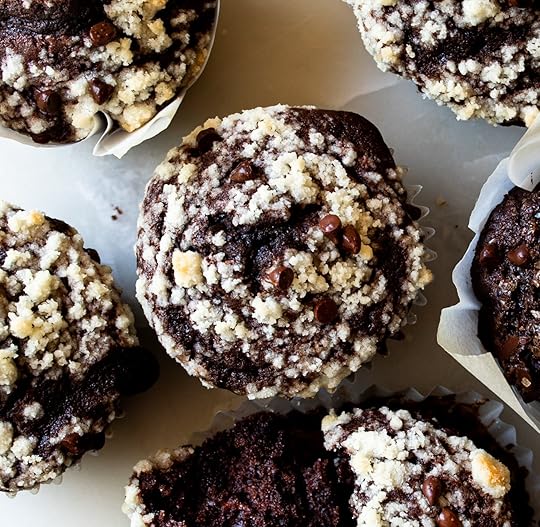 A close-up overhead photo of rich double chocolate zucchini muffins featuring a thick, buttery streusel crumb topping and sprinkled with mini chocolate chips.