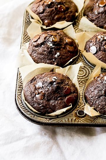 Close-up of moist bakery-style double chocolate zucchini muffins with chocolate chips and a sprinkle of sea salt in a vintage metal muffin tin, on a white linen.