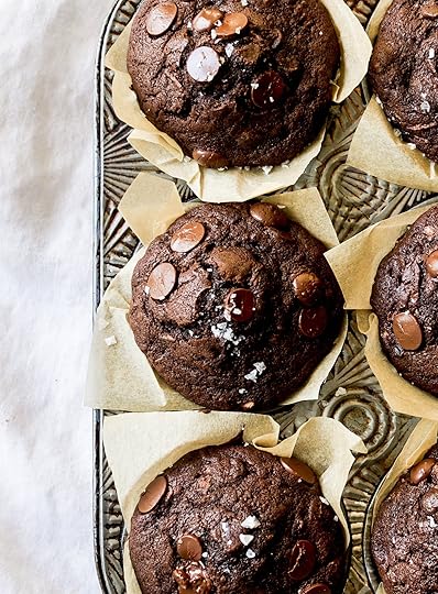Overhead close-up of deeply rich, freshly baked double chocolate zucchini muffins featuring prominent chocolate chips and a delicate sprinkle of flaky sea salt, cooling in a vintage metal muffin pan.