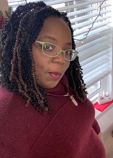 Queer author Ruby Dare, a sassy, fat Black woman with green glasses and a red sweater, with curly hair to her shoulders.