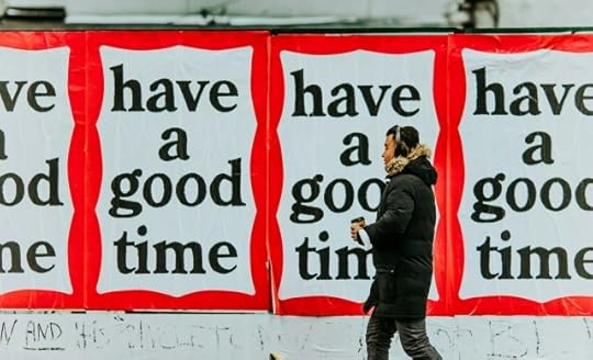 A person walking by signs reading “have a good time.” You’re allowed moments of good amid this bad.