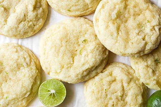 Close-up of soft, pillowy key lime cookies with a crinkle top and a fresh halved key lime.