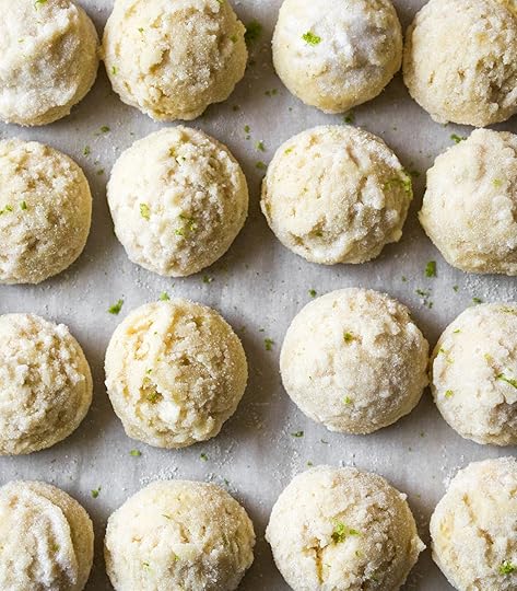 Unbaked key lime cookie dough balls coated in sugar and lime zest, arranged in rows on a baking sheet.
