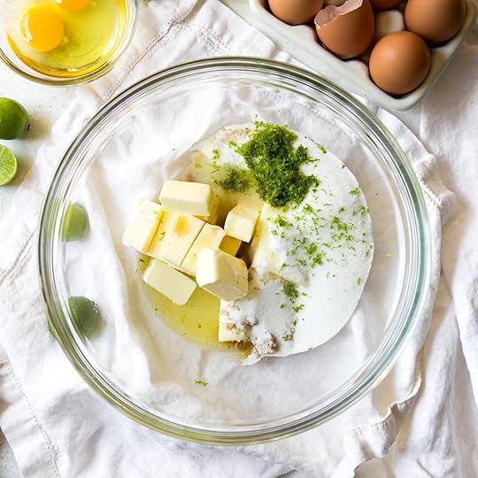 Cubed butter, granulated sugar, brown sugar, and fresh key lime zest in a glass mixing bowl, ready to be creamed together for key lime cookies.