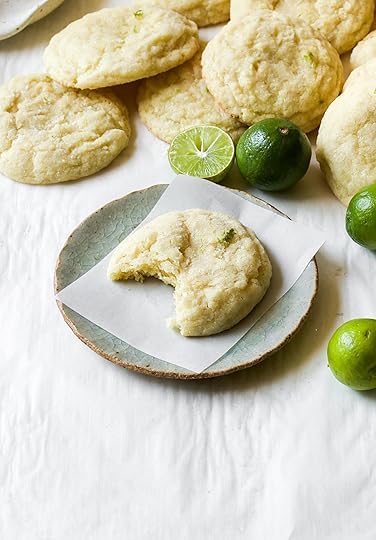 Delightfully soft key lime cookie with a missing bite on a rustic plate, surrounded by whole and halved fresh limes.