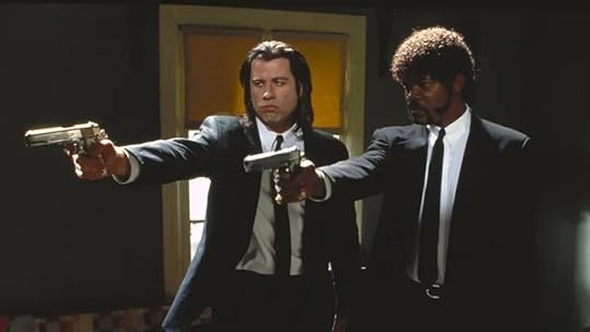 Two men in dark suits and ties stand side by side in a dimly lit room, each pointing a handgun with serious expressions. The man on the left has long dark hair, while the man on the right has a short afro and goatee. Behind them, sunlight streams through a window with orange blinds, casting dramatic shadows in the room.