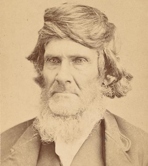 Orvill Ball, with long hair pulled forward and curled over the top of his head, in a head-and-shoulders portrait.