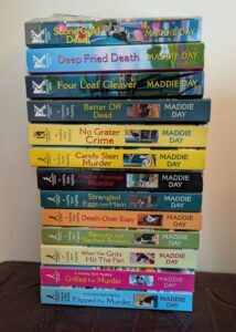 Stack of Local Foods Mystery Series books shown sideways with visible spines and titles.