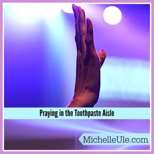 A hand lifted in prayer against a purple background.