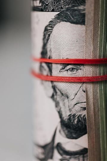 Close-up of a rolled U.S. five-dollar bill wrapped with red rubber bands, showing Abraham Lincoln’s face.