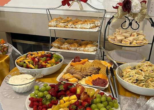 table set for party with sandwiches, cheese, crackers, fruit salad, pasta salad, and fresh fruit
