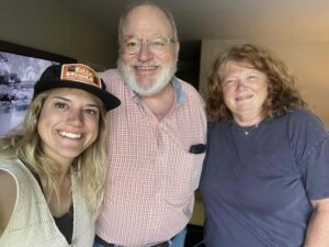 Husband and wife standing with their adult daughter