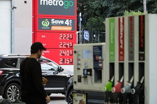 A man in a black cap and top walks through petrol station.