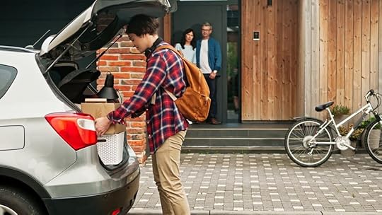 A stock photo of two parents watching as their son loads boxes into a car.