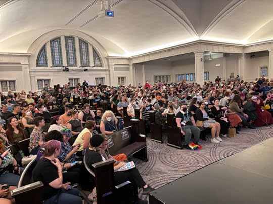 A large audience of people sitting in wooden pews under a vaulted ceiling