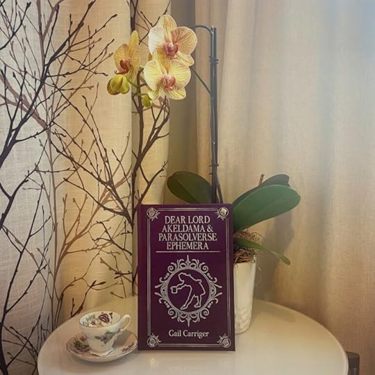 Dear Lord Akeldama and the Parasolverse Ephemera book next to a flower