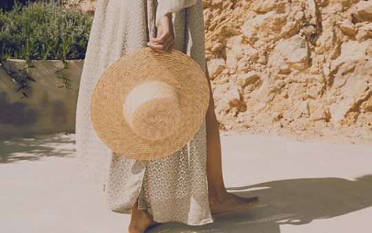 woman on the beach holding a hat