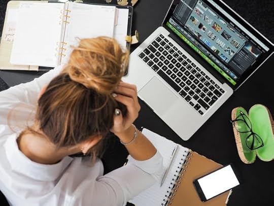 Stressed woman at desk surrounded by work tools, symbolizing the mental clutter that blocks clarity on how to control my reality