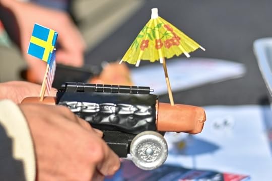 Hot dog decorated with flags and a parasol, ready to race