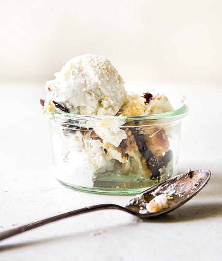 A glass jar with layers of no-churn s'mores ice cream, featuring a scoop on top and a spoon inside. The dessert includes visible pieces of chocolate, graham crackers, and toasted marshmallows.