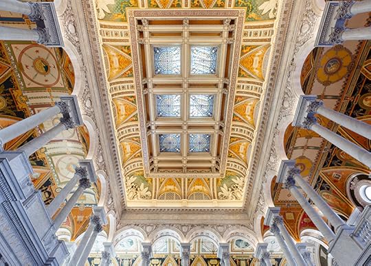 A wide angle view of the stained glass ceiling in the Great Hall, wilth marble columns on all sounds and a painted ceiling surrounding the glass.
