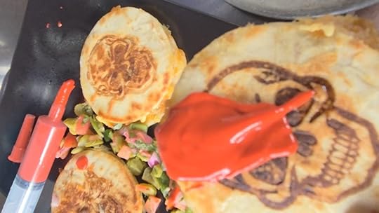 Mini quesadillas with skulls on them and a syringe with blood red sauce shown up close with sauce on one