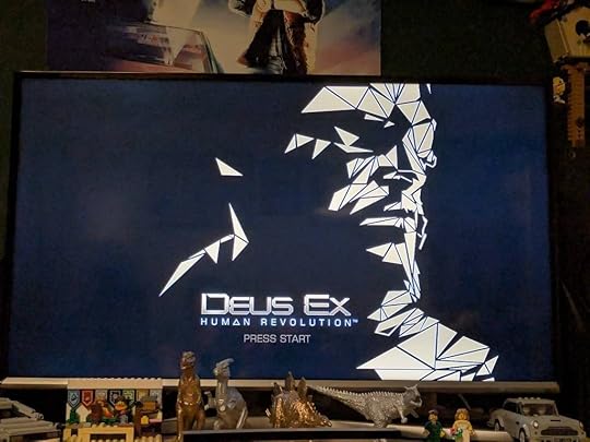 The title screen of Deus Ex: Human Revolution on a TV: a man's face rendered in golden polygons