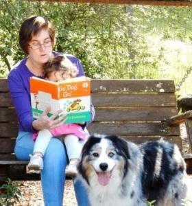 Grandmother reading Go Dog, Go to a child with a dog looking on
