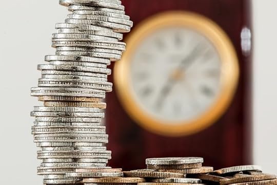 Leaning stack of silver coins in front of a blurred clock, symbolizing trading time for money