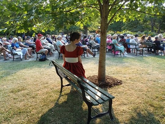 Sarah Emsley on a park bench, with other attendees in the background