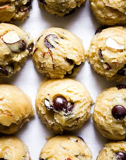 lose-up overhead view of perfectly scooped balls of almond chocolate chip cookie dough with visible chocolate chips and sliced almonds, ready for baking.